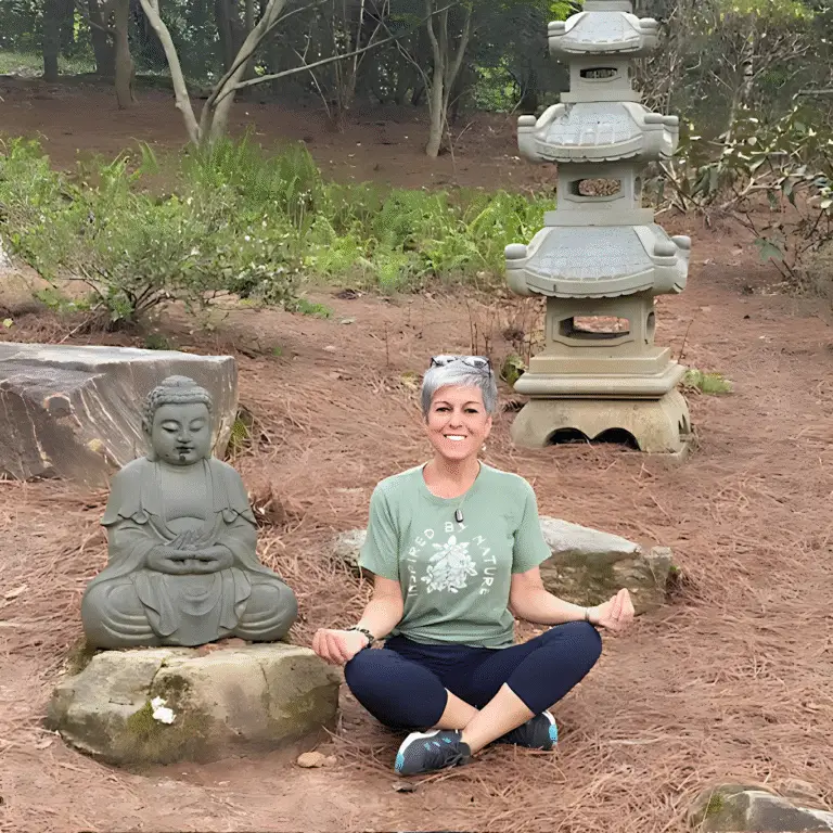Tina Brunetti-Smith sitting in front of a statue meditating
